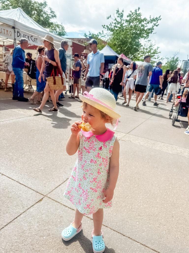 Rose eating a croissant at the Boulder Farmers Market.  Image by Katherine Rose Woller